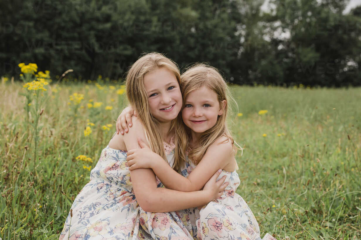 two-little-sisters-hugging-each-other-on-a-meadow-NMSF00150