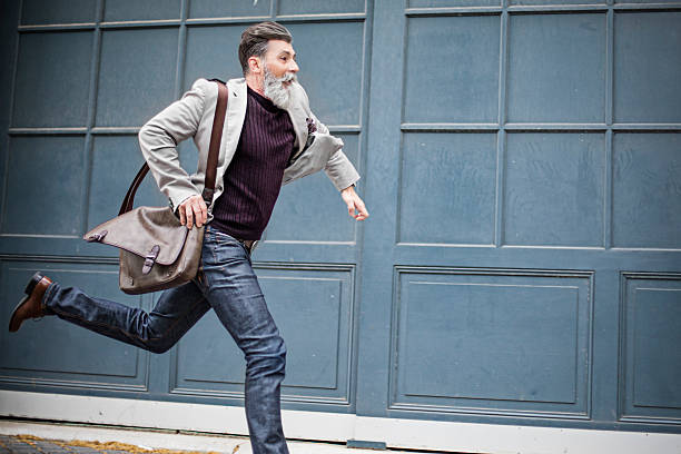 Mature businessman with a handbag running on the city street